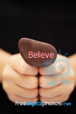 Hand Holding Believe Stone Stock Photo