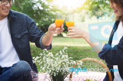 Happy Couple Toasting Wineglasses While Sitting On Picnic Blanke… Stock Photo