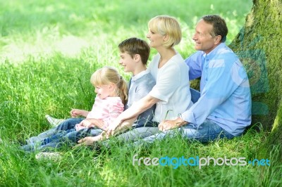 Happy Family Relaxing In Park Stock Photo