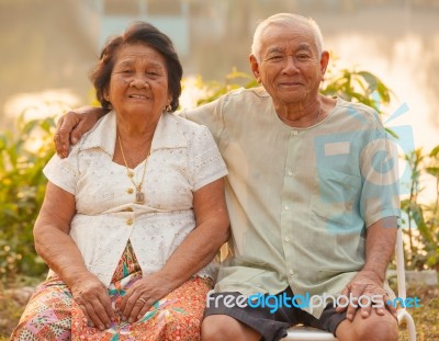 Happy Senior Couple Sitting Outdoors Stock Photo