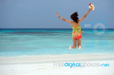 Happy Young Woman Jumping On The Beach Stock Photo