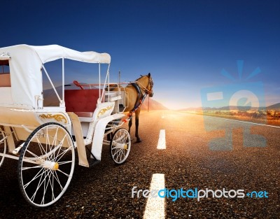 Horse And Classic Fairy Tale Carriage On Asphalt Road Perspective To Beautiful Land Scape With Sun Rising Sky Stock Photo
