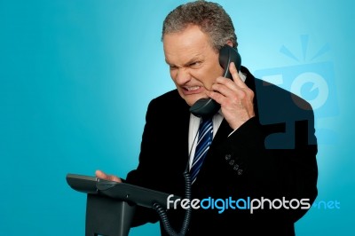 Irritated Businessman Communicating On Phone Stock Photo
