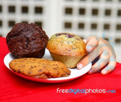 Kid Stealing Muffin From Table Stock Photo