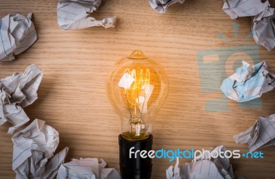 Light Bulb With Crumpled Paper On Wood Background Stock Photo