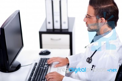 Male Doctor Working With Desktop At His Desk Stock Photo