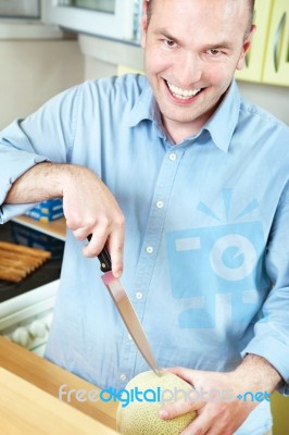 Man And Melon In Kitchen Stock Photo