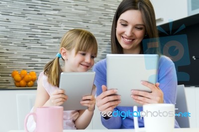 Mother And Daughter Using A Digital Tablet In Kitchen Stock Photo