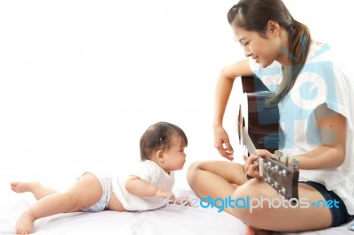 Mother Is Playing A Guitar For Her Baby Stock Photo
