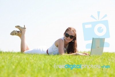Oung Female Lying On The Grass In The Park Using A Laptop Stock Photo