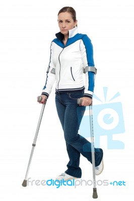 Pensive Looking Woman Using Crutches To Walk Stock Photo