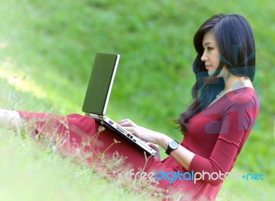Pretty  Woman With Laptop On Green Grass At The Garden Stock Photo