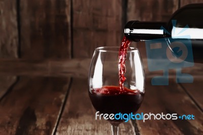 Red Wine Is Poured From Bottle To Glass Stock Photo