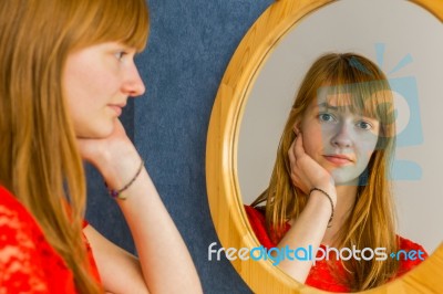 Redhead Teenage Girl Looking In Mirror Stock Photo