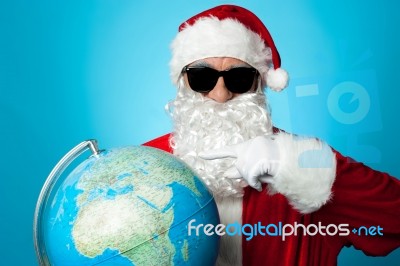 Santa Pointing At Globe Map Stock Photo