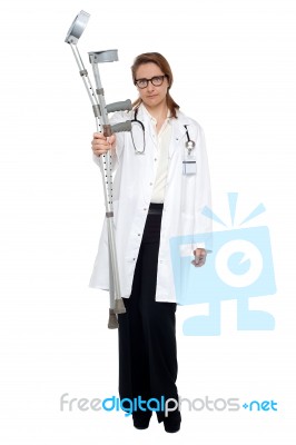 Serious Faced Doctor Holding Crutches Stock Photo