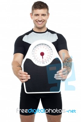 Smart Young Fit Male Showing Weighing Machine Stock Photo