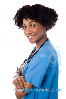 Smiling Female Physician Standing Sideways With Folded Arms Stock Photo