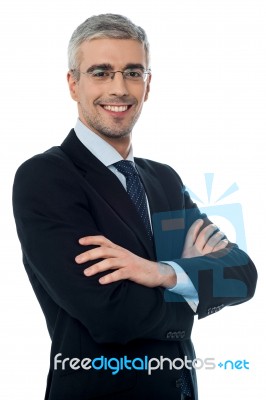 Smiling Senior Businessman With Arms Crossed Stock Photo