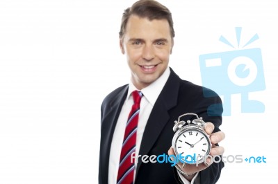Smiling Young Consultant Showing Alarm Clock Stock Photo