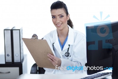 Smiling Young Doctor With Clipboard In Hand Looking At The Camera Stock Photo