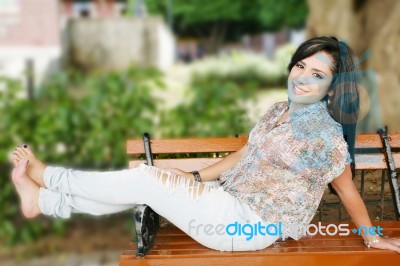 Smiling Young Girl Sitting In Park Stock Photo