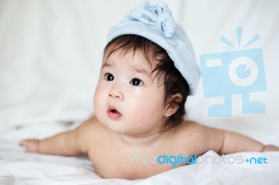 Sweet Newborn Baby In Blue Bobble Hat Lies On Bed Stock Photo