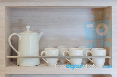 Teapot And Cups On Wooden Shelf Stock Photo