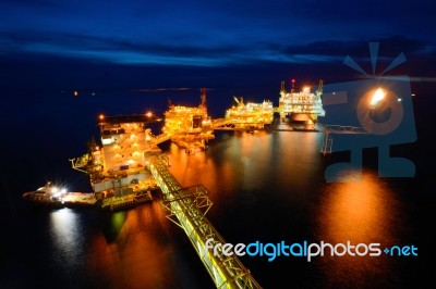 The Supply Boat Is Working At Large Offshore Oil Rig At Night Stock Photo