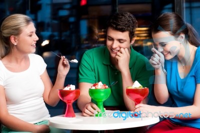 Three Friends Enjoying Tempting Dessert Stock Photo