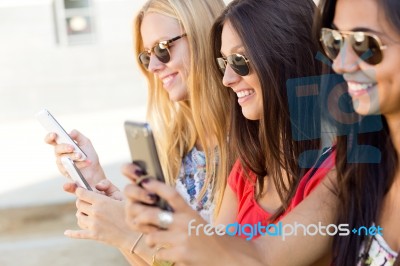 Three Girls Chatting With Their Smartphones At The Campus Stock Photo