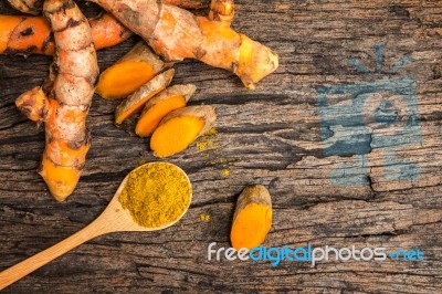 Turmeric Powder In Spoon And Roots On Wooden Plate Stock Photo