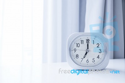 White Square Clock On White Bed Stand With White Curtain Background, Morning Time In Minimal Style Decoration Stock Photo