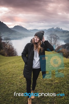 Woman On A Meadow At Sunset Over The Lake Stock Photo