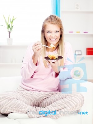 Woman On Sofa Eating Cake At Home Stock Photo
