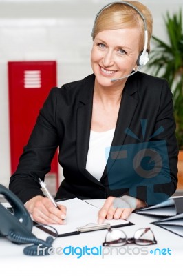 Woman Wearing Headset Writing Stock Photo