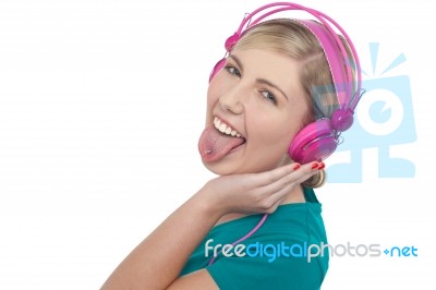 Woman With Headphones On Sticking Her Pierced Tongue Out Stock Photo