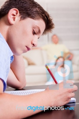 Young Boy Writing In Notebook Stock Photo