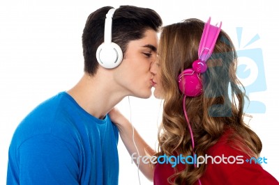 Young Couple Enjoying Music And Kissing Stock Photo