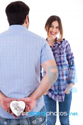 Young Man Hiding The Gift From Her Girlfriend Stock Photo