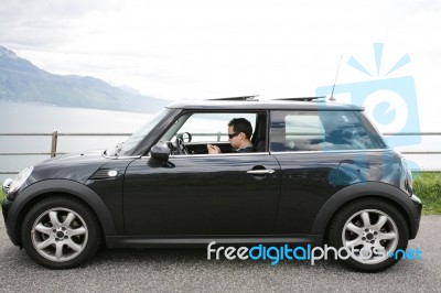 Young Man In His Fancy Car Chatting With His Device Up The Hills… Stock Photo