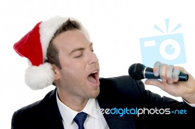 Young Man Singing Into Microphone With Santa Cap Stock Photo
