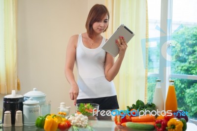 Young Woman Following Recipe On Digital Tablet Stock Photo