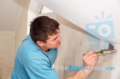 Young Worker Painting Wall With Glue Stock Photo