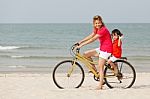 Asian Son And Mother Riding Bicycle On Beach Stock Photo