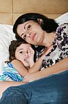 Beautiful Young Mother And Her Daughter On The Bed Stock Photo