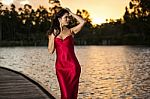 Beautiful Young Woman In The Gardens Wearing A Long Silk Red Dress Stock Photo