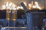 Champagne Flutes And Bottle By The Fire Stock Photo