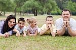 Cheerful Family Of Five Lying On Lawn Stock Photo