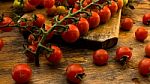 Cherry Tomatoes On Display On Wooden Chopping Board And Wooden Table Stock Photo